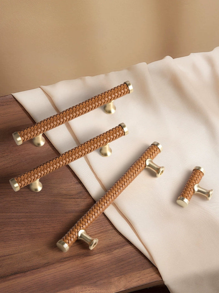 Brown woven leather drawer pulls with gold tone hardware on wood and fabric.